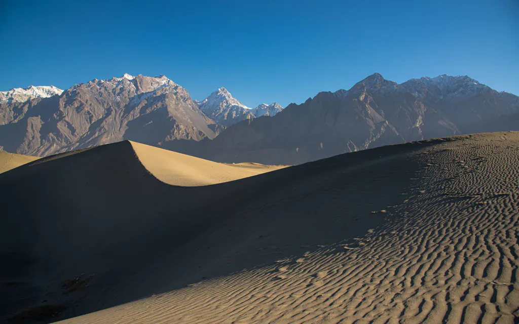Sand dunes of the Katpana cold desert beneath snowy peaks in Skardu