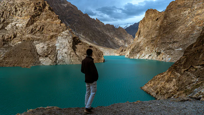 A traveller looking out over the turquoise water of Attabad Lake
