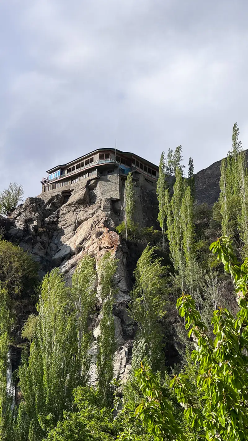 Baltit Fort on its rocky hill above green trees in Karimabad, Hunza