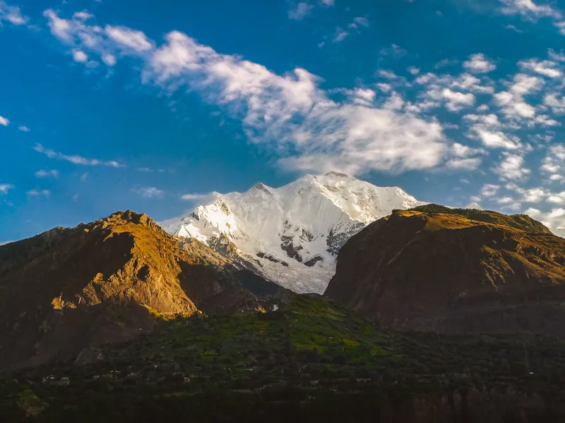 Snow-capped Rakaposhi rising behind brown ridges in Hunza